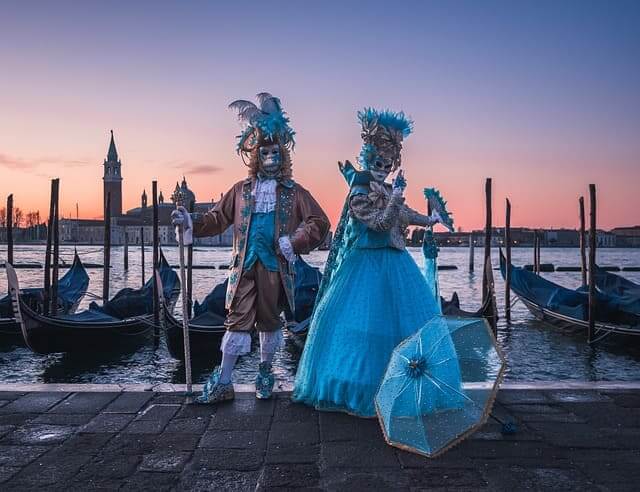 Kostümierte Karnevalsbesucher bei Sonnenuntergang in Venedig