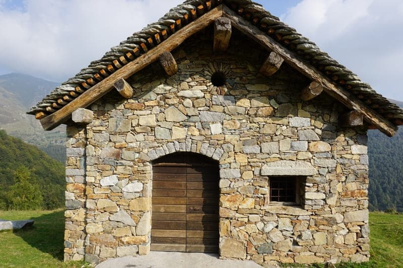 alpines Steinhaus mit traditioneller Holztür im Biellese