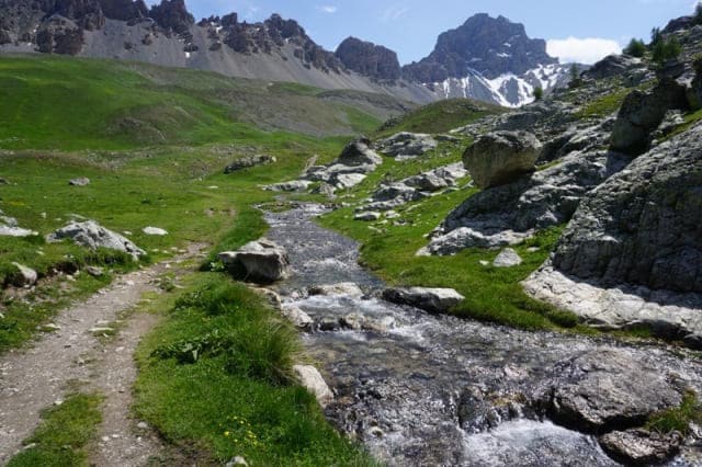 Der Bach Oronaye schlängelt sich zwischen Wiese und Felsen