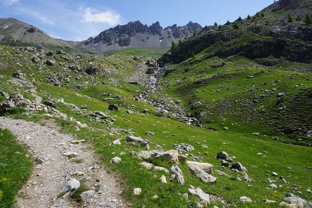 Der Weg führt vorbei an Wiesen und gigantischen Gebirgsfelsen